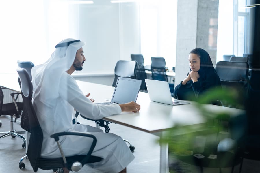 man woman with traditional clothes working business office dubai 5 1 2